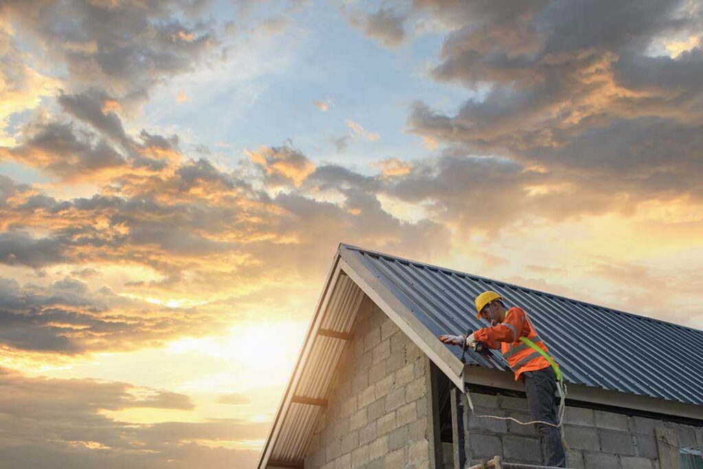 Homeowner examining roof damage from the ground after a storm while checking fallen shingles and a gutter.